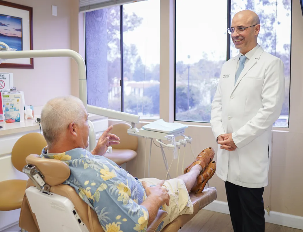 Dr. Reshad standing beside a relaxed patient in one of our treatment rooms