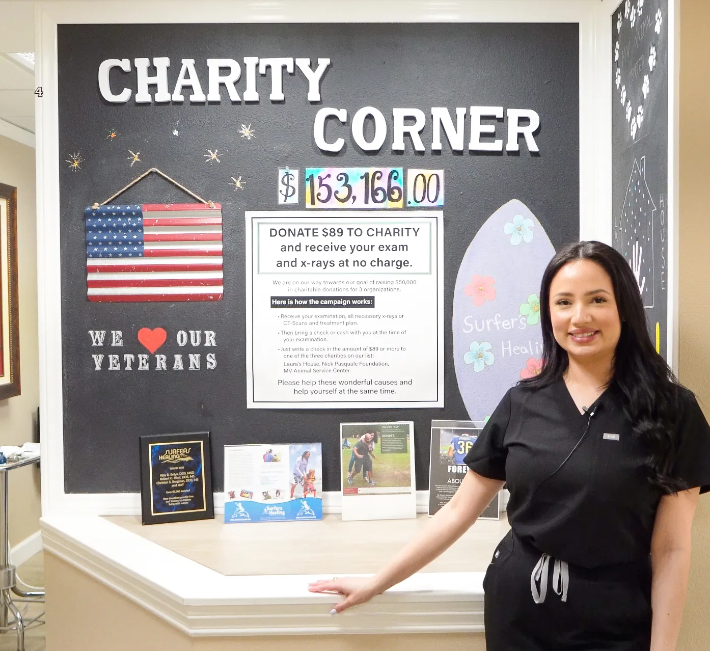 A team member beside the Charity Corner display at OC Perio & Implants Dental Group